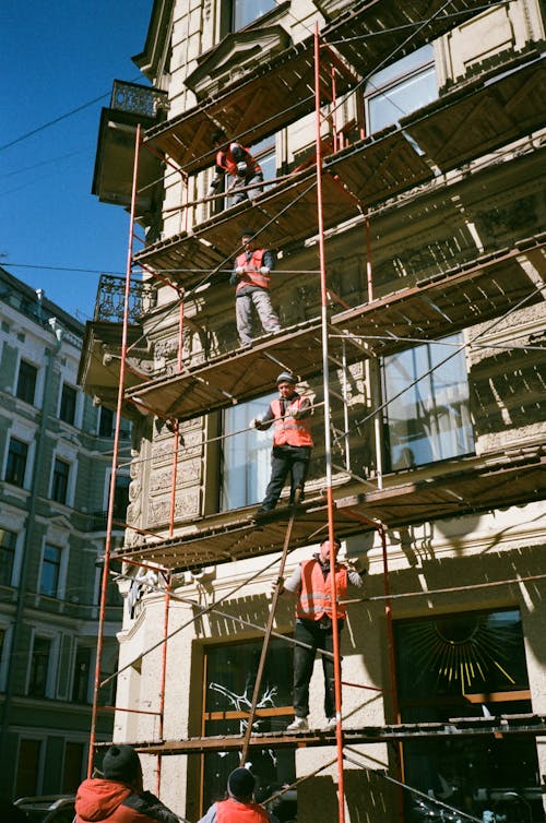 Para pekerja berdiri di atas scaffolding